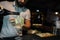 Barman pours champagne from a bottle into a glass at a nightclub at the bar. Professional barman making a cocktail. Lifestyle.