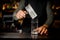 Barman putting a big rectangular piece of ice into a glass