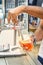 Barman`s hand holds a large glass in which fresh amber beer is poured with foam