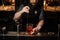 Barman stirring a red cocktail with a steel spoon in the measuring glass cup