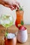 Barmans hand decorating four different assorted cocktail drinks made with alcohol and fruit served in unique glasses