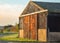 Barn on farmland with metal red and rusty doors.