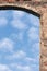 Barn gate door arch and sky, stone wall closeup, vertical bright white summer clouds cloudscape copy space background, plastered