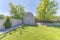 Barn tool shed at the corner of a fenced backyard against the trees and shrubs at the back