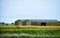 Barn or warehouse between meadows, and farmland. Blue sky for text