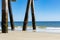 Barnacle covered concrete pier pilings by blue ocean waters, bright blue sky