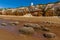 Barnacle-encrusted rocks with a backdrop of the white, red and orange stratified chalk cliffs at Old Hunstanton, Norfolk, UK