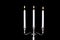 Baroque silver candlestick with white paraffin candles burning isolated on black background