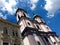 Baroque style double church towers with clocks and green copper metal roofs. blue sky.