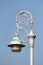 Baroque style light grey public light mounted on rusted wrought iron decorated pole