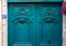 Baroque style sculptural details of gorgeous antique wooden door painted in beautiful aquatic blue color. Top part of doorway