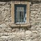 Barred window in old stone house wall