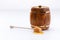 A barrel of honey and a wooden spoon with a drop of tasty liquid on a white background