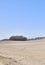 Barren farm land with trees and blue sky background. A desolate agricultural farmland caused by summer heat droughts and