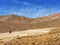 Barren mountain landscape with brownish alpine grass and blue sky abstract background