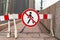 Barrier blocking sidewalk and sign with picture of crossed-out man prohibiting the passage of pedestrians, because the