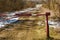 The barrier blocks the passage on a rural dirt road. Closed park area. The first snow on the dry grass along the roadside