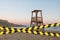 Barrier tape - quarantine, isolation concept, entry ban. Do not cross. A lifeguard tower on the mediterranean beach at sunset
