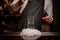 Bartender adding some drops of brown bitter into a cocktail glass