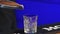 Bartender adds ice cubes to the glass in slow motion, making the cocktail at the bar counter, blue backlight.