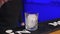 Bartender adds ice cubes to the glass in slow motion, making the cocktail at the bar counter, blue backlight.