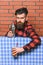 Bartender concept. Man in checkered shirt on brick wall background. Barman with long beard and mustache and stylish hair