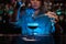Bartender girl adding to a brown cocktail a flamed badian with tweezers in the blue light
