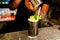 Bartender hands pouring icing sugar on lost lake cocktail  with mean leaves inside night cocktail bar