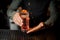 Bartender holding a glass with summer light sour cocktail with pink peach liquor decorated with flower