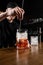 Bartender mixes gin, campari, and sweet vermouth to prepare the Negroni alcoholic cocktail. Bartender prepares