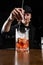 Bartender mixes gin, campari, and sweet vermouth to prepare the Negroni alcoholic cocktail. Bartender prepares