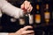 Bartender opening a wine bottle with corkscrew in restaurant with wine shelves.