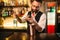 Bartender pouring alcohol beverage in metal glass