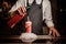 Bartender pouring alcoholic sparkling water into a glass with sweet red berry summer cocktail with foam