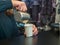 Bartender pours the coffee into the paper glass. Photo behind the bar counter with blurred background and soft focus