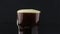 Bartender pours dark beer from a bottle into a glass. A man fills a glass with dark beer.