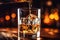 The bartender pours whiskey into a glass with ice on the bar counter. close-up. Blurred background. Elite alcoholic drink