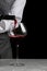 Bartender pours wine in glass on dark background