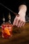 Bartender puts a drop of Negroni alcoholic cocktail on his hand and tastes it. Barman prepares classical Negroni