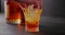 bartender puts ice sphere for cooling into a glass of whiskey on a background of bottles