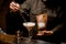 bartender s hand holds tweezers with coffee bean and decorates by it glass with frothy cocktail