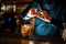 Bartender sprinkling orange peel juice into a cocktail glass