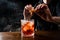 Bartender squeezes orange peel and sprinkles juice over the Negroni in the glass. Bartender prepares classical Negroni