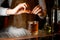 Bartender squeezes orange zest in whiskey glass