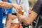 Bartender on the street bar handing a plastic glass of beer to a