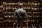 Bartender at wine cellar full of bottles with exquisite drinks