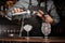 Bartenders hands pouring alcoholic drink into a glass using a jigger to prepare a cocktail