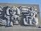 Bas-relief on the facade of the Palace of youth. The building, clad in glass and stone, is raised above the square on a granite