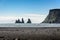 Basalt rock Troll on black beach with blue sky, Reynisdrangar, V