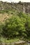 Basalt wall on the banks of the Azat river flowing among trees and stones through the Garni gorge in Armenia